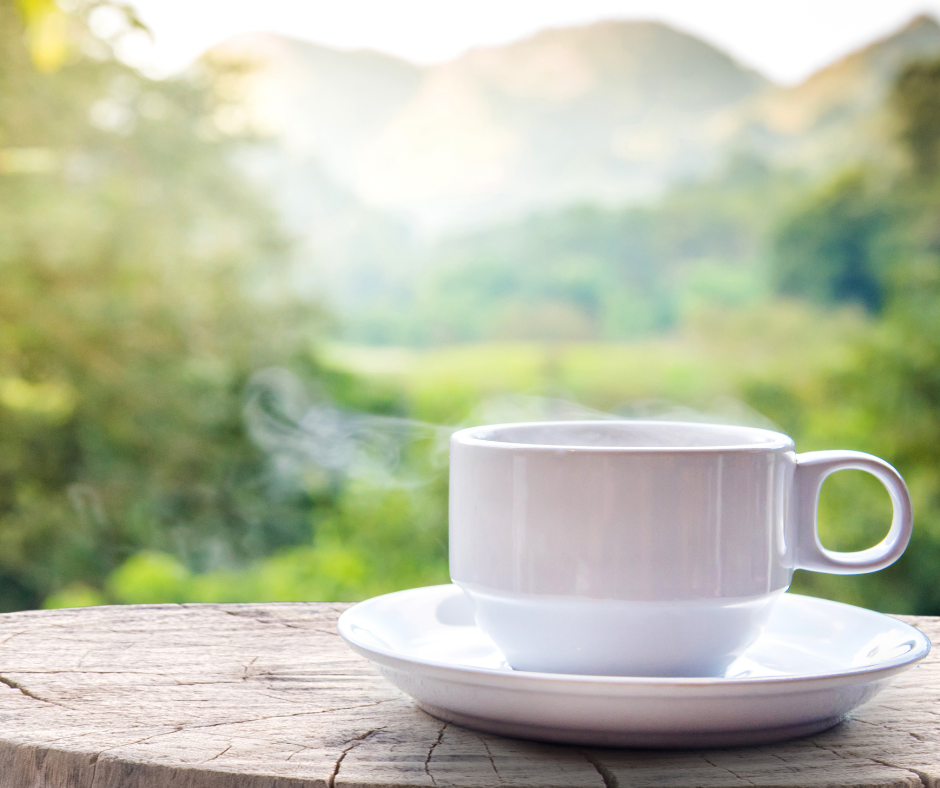 white coffee cup on table outside with a mountain view vacation planning