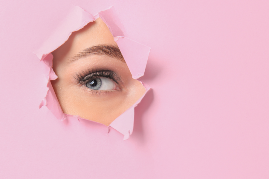 a woman peeking through a hole because she is afraid of being seend