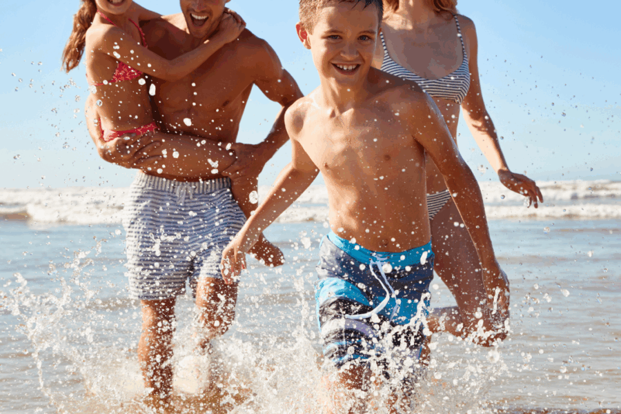 a family of four running in the surf at the beach on vacation